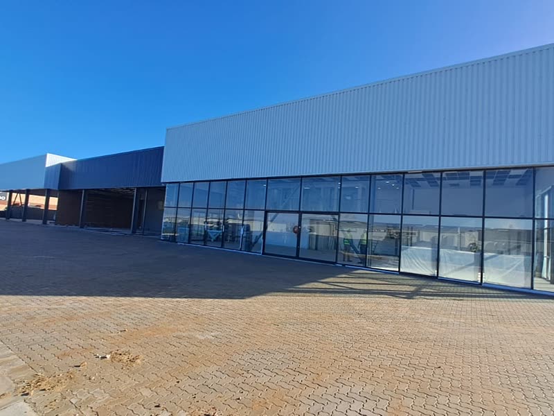 Completed retail building with full-height shopfront glazing and paved apron