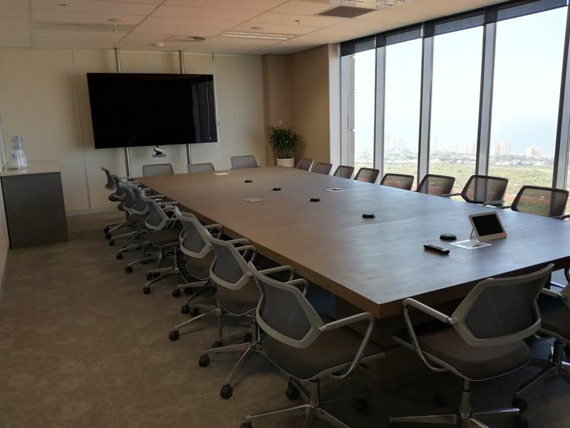 Completed boardroom with a long table, screen and full-height glazing