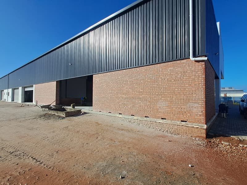 Long building with dark profile cladding over a face-brick base