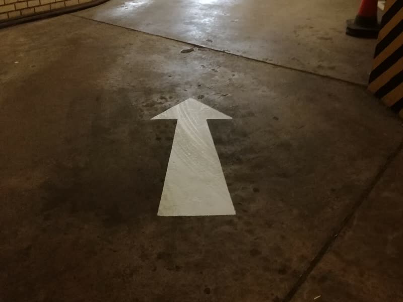 Directional floor marking newly applied across a parking deck