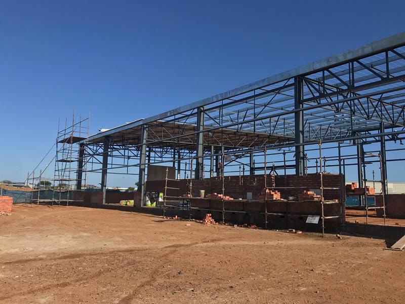 Steel frame with brickwork under way and site teams at work