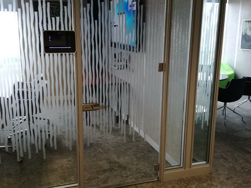 Glazed meeting room with a wall-mounted screen on a completed office floor