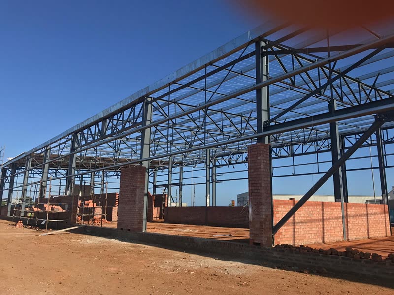 Erected steel portal frames over brick columns on a cleared site