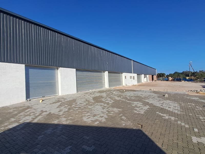 Row of completed industrial units with roller doors and a paved yard