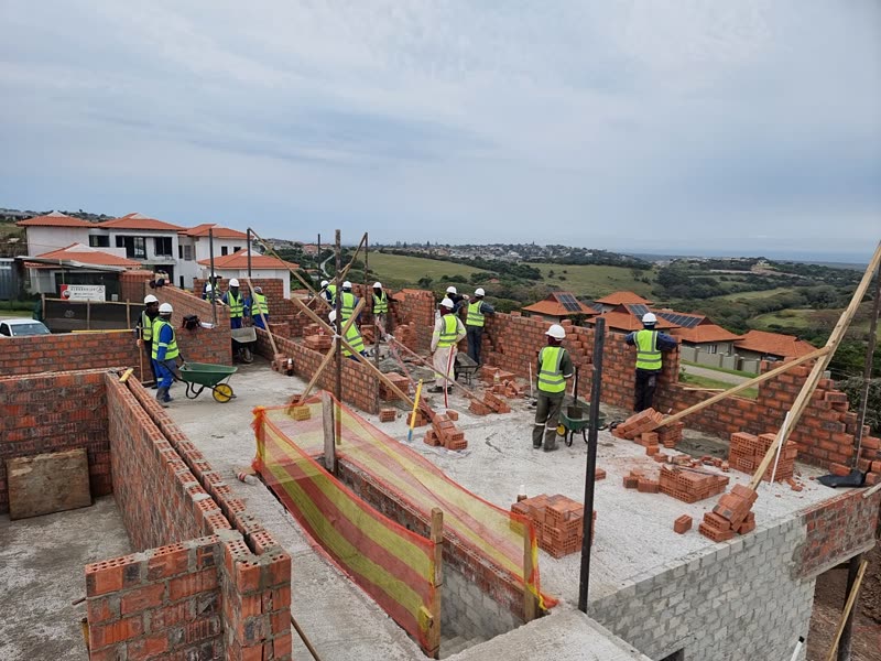 Bricklaying team raising the superstructure on a slab within a coastal estate