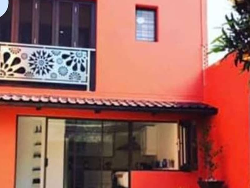 Double-storey building with a deep red painted façade and decorative balcony screen