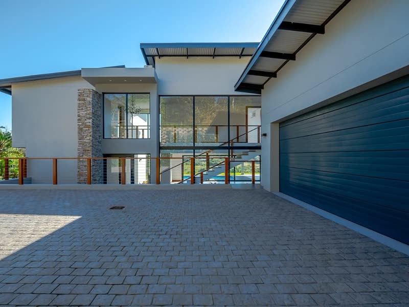 Double-storey home with stone cladding, glazing and a paved forecourt