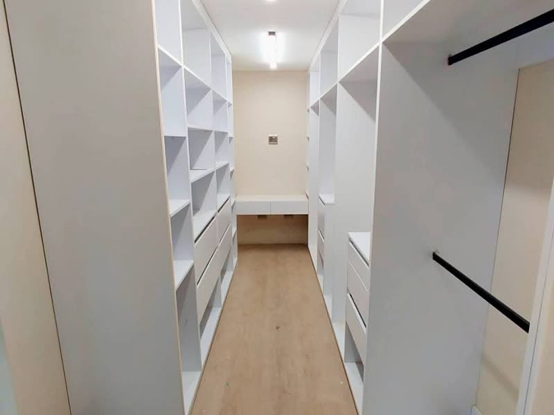 Full-length dressing room with fitted white joinery either side of a timber floor