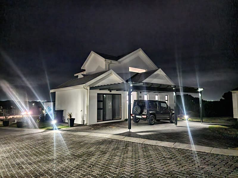 Completed home floodlit at night with vehicle under the carport