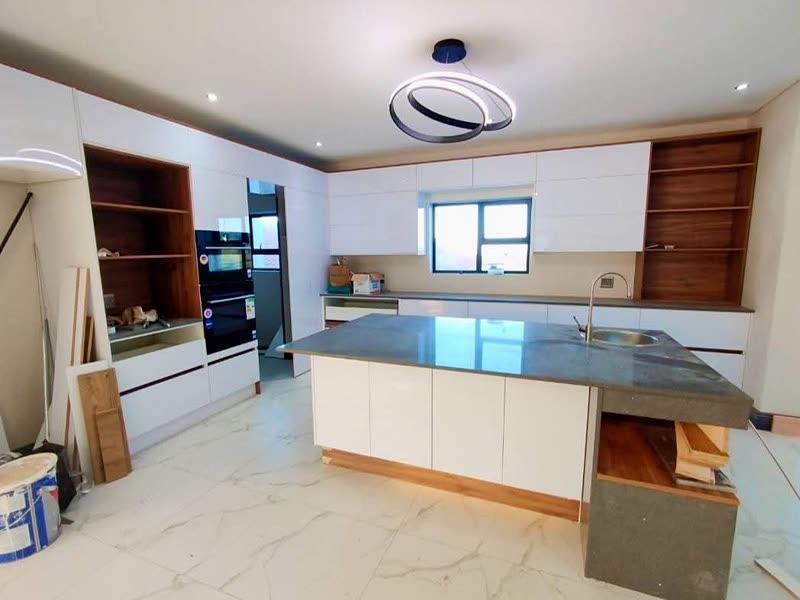 Fitted kitchen with an island, stone tops and marble-effect floor tiling nearing completion