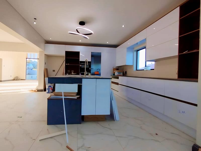 Kitchen with a navy island, timber joinery and marble-effect tiling being finished