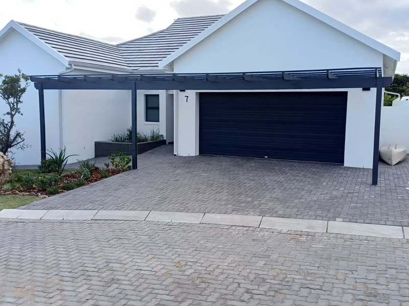 Single-storey home with a steel pergola over the garage and block-paved driveway