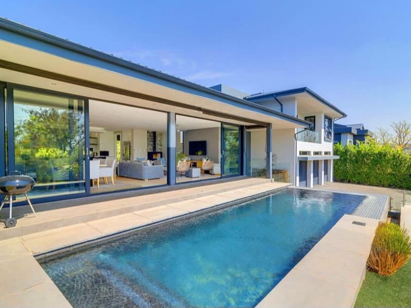 Completed high-end home with stacking doors opening onto a pool and landscaped garden