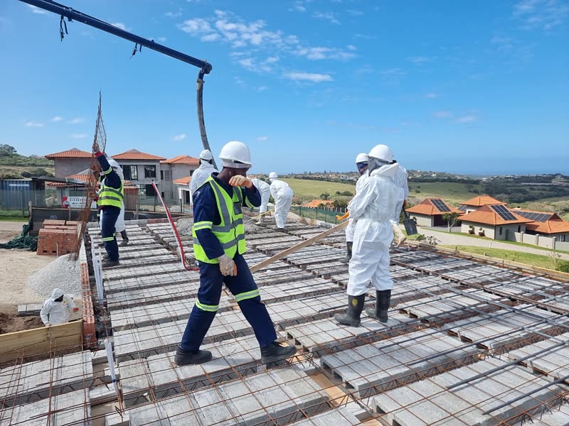 Site team placing pumped concrete across a suspended slab