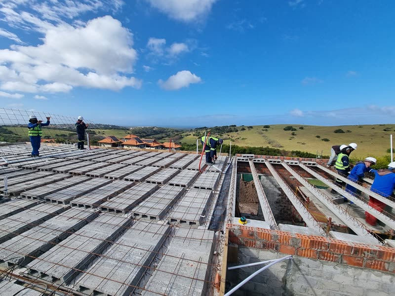 Rib-and-block deck laid out and reinforced ahead of the topping, coastal estate beyond