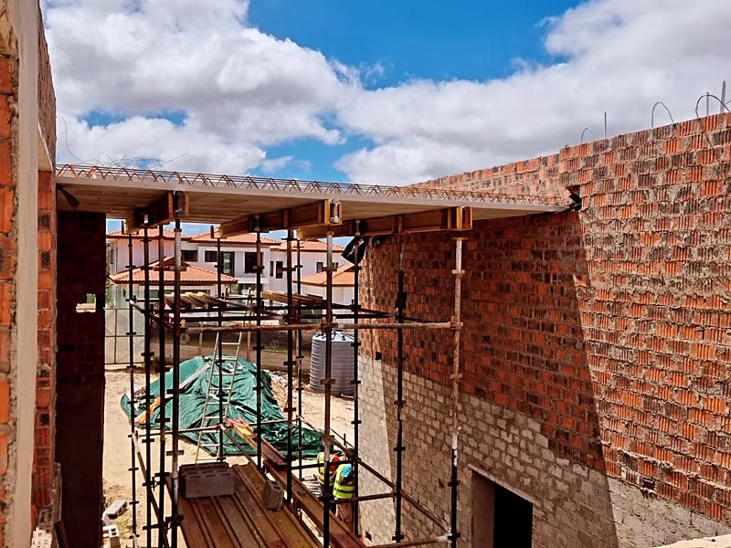 Face-brick walls rising with scaffolding in place and the roof structure starting