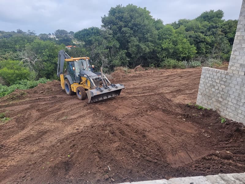Backhoe loader clearing and levelling a site platform ahead of foundations