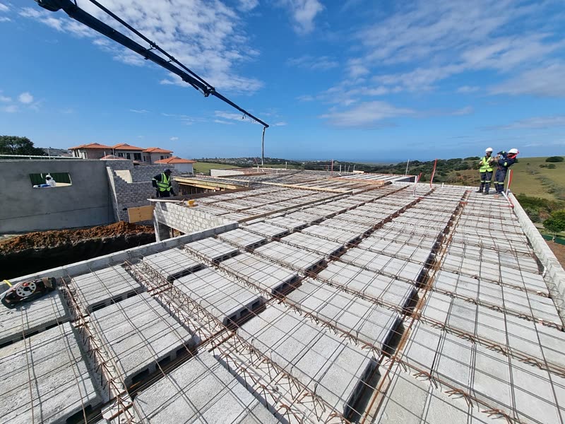 Reinforcement laid out across a suspended slab before the pour, coastal estate beyond